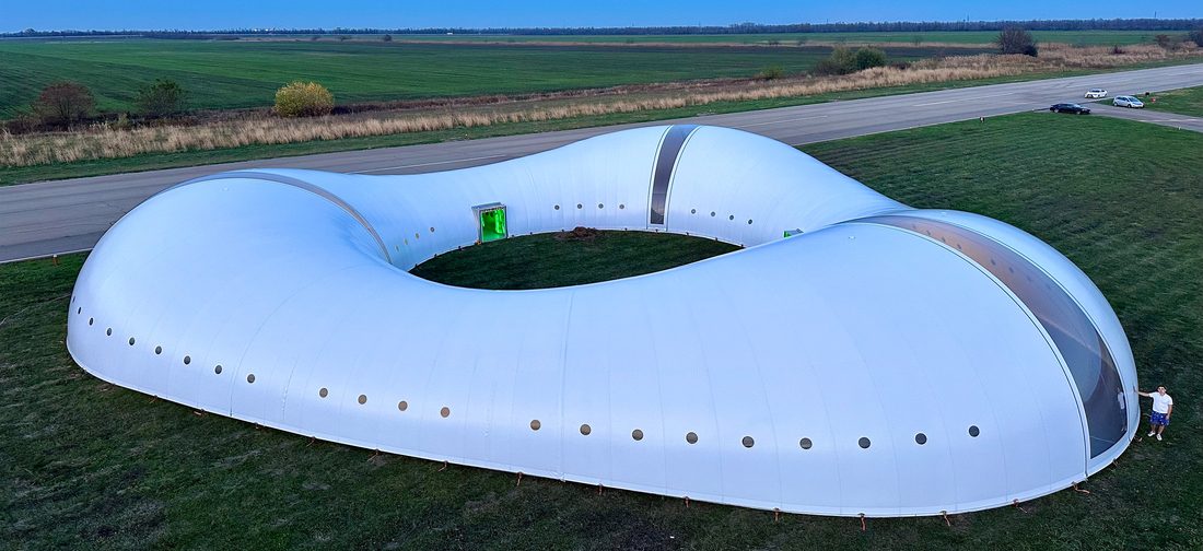 Bâtiment textile blanc aux formes organiques installé en pleine campagne.