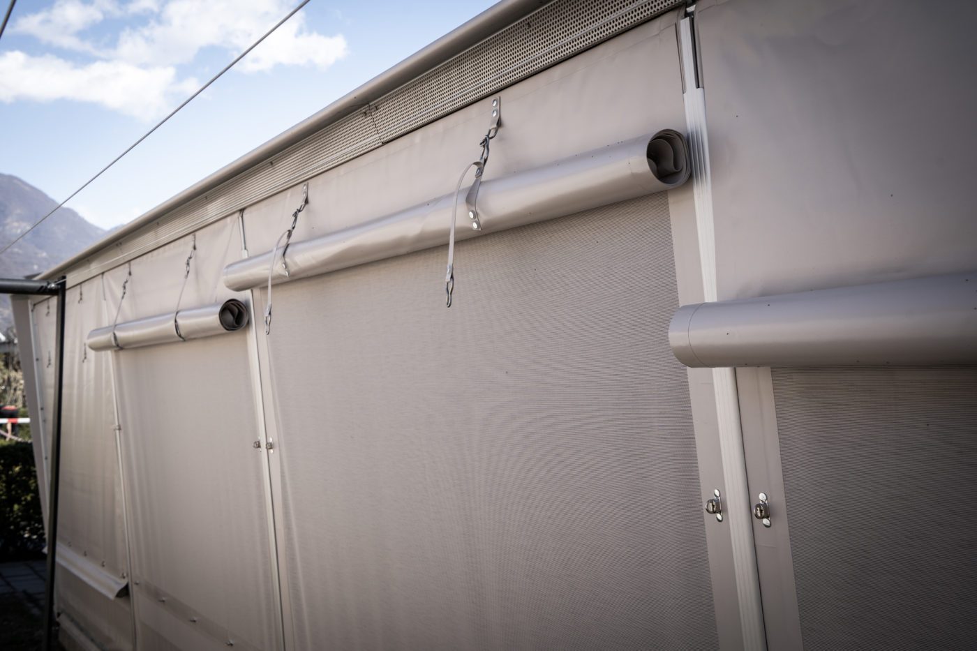 Close-up of roll-up textile sidewalls attached to a metal frame.