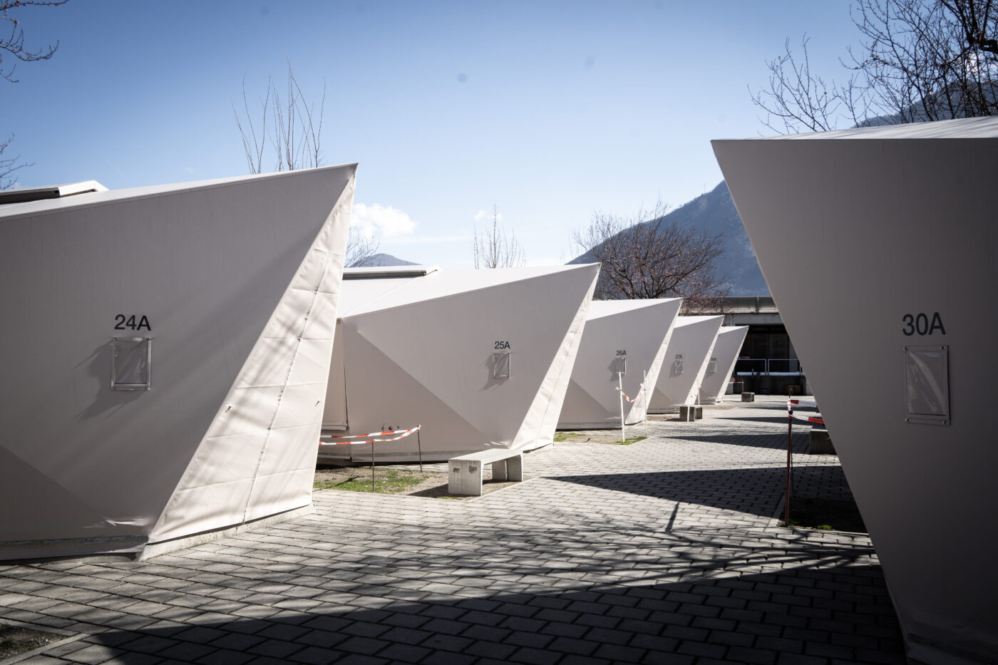 Row of white modular shelters installed outdoors with numbered units.