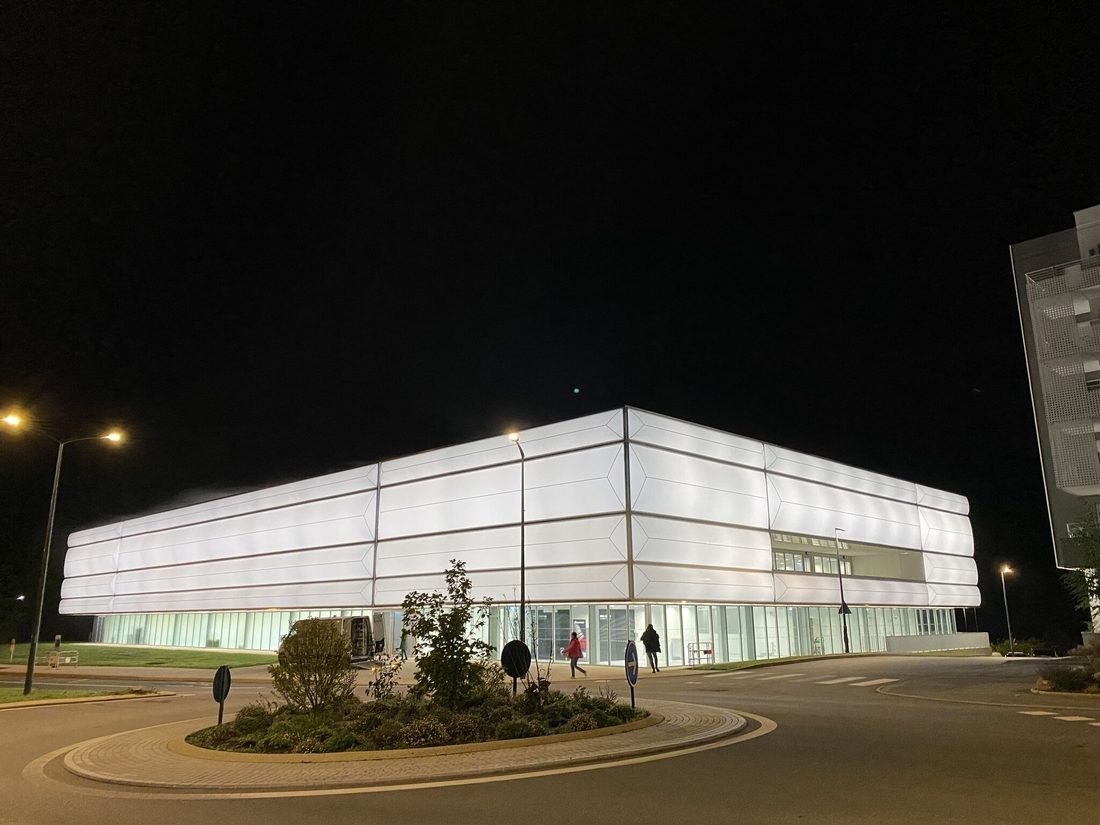 Night view of Hennebont Table Tennis Centre illuminated through its translucent textile façade