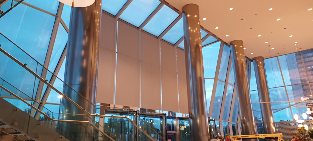 Hall d'immeuble de bureaux équipé de stores enrouleurs sur une façade entièrement vitrée.
