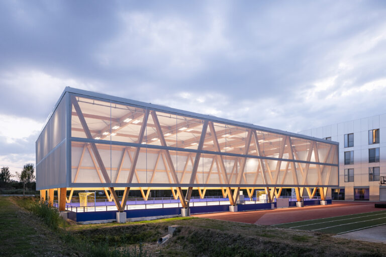 Bâtiment sportif avec façade textile translucide Serge Ferrari éclairée de nuit