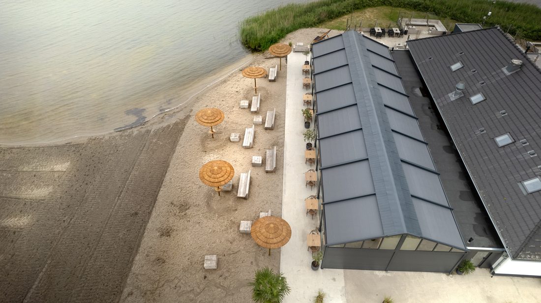 Glazed pavilion with Serge Ferrari Soltis 96 Proof shading overlooking a sandy recreational area