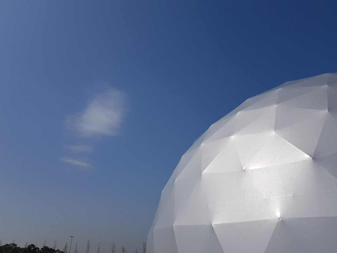 Structure Flexlight en forme de dôme géodésique blanc installée dans un parc verdoyant sous un ciel ensoleillé