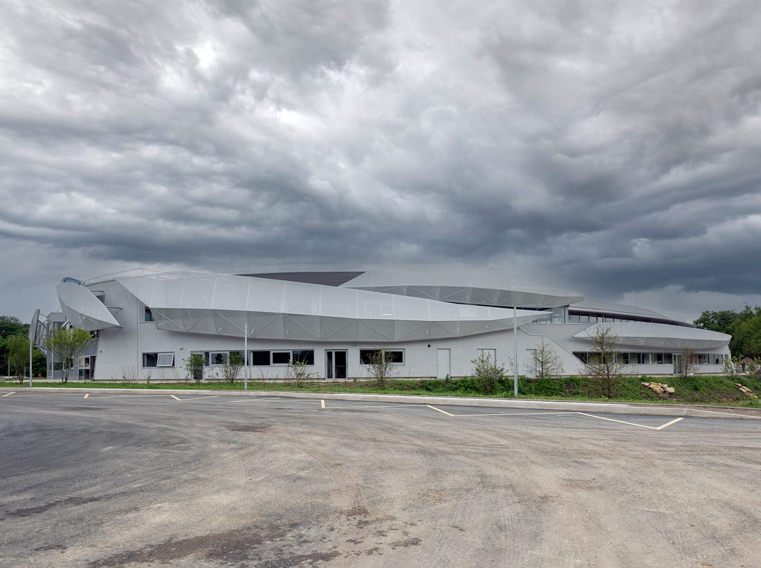 Exterior view of Aquatic Center of Taverny with transparent roof arch and geometric façade design