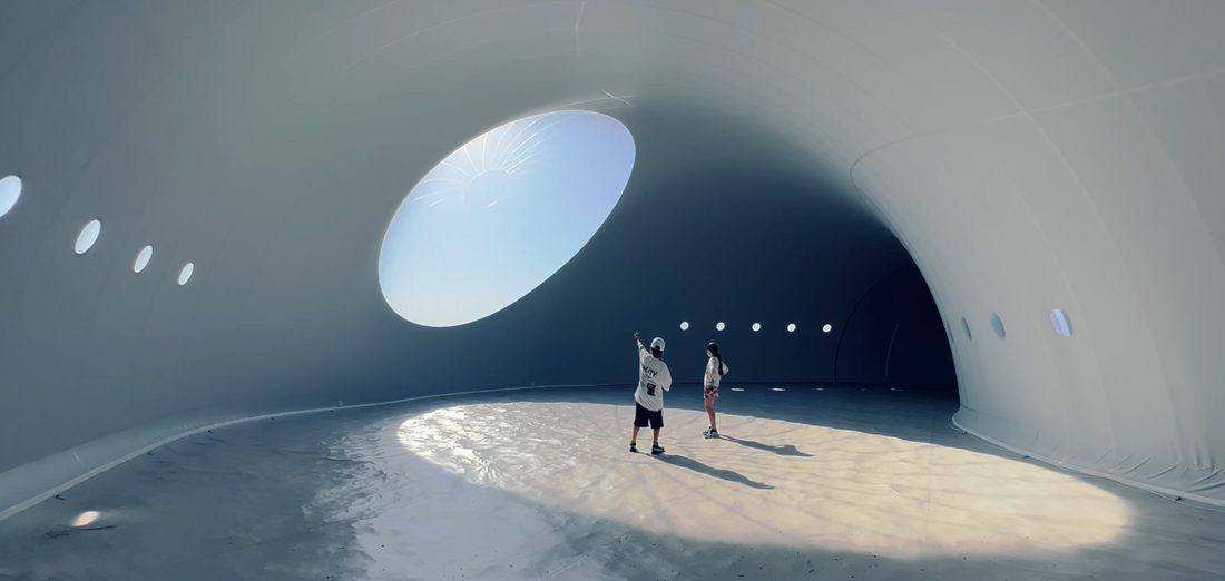 Espace intérieur sous membrane textile avec oculus laissant entrer la lumière naturelle.