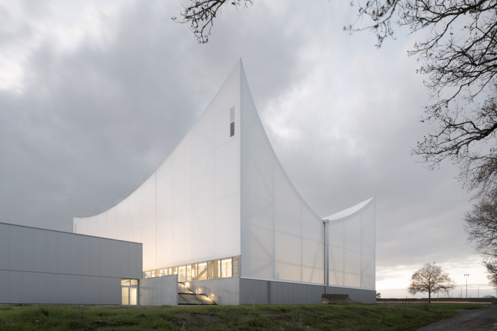 Bâtiment sportif de la Bouëxière, habillé d’une enveloppe textile translucide blanche, aux volumes élancés et courbes, réalisé avec les membranes 902 S2 et 1002 S2.