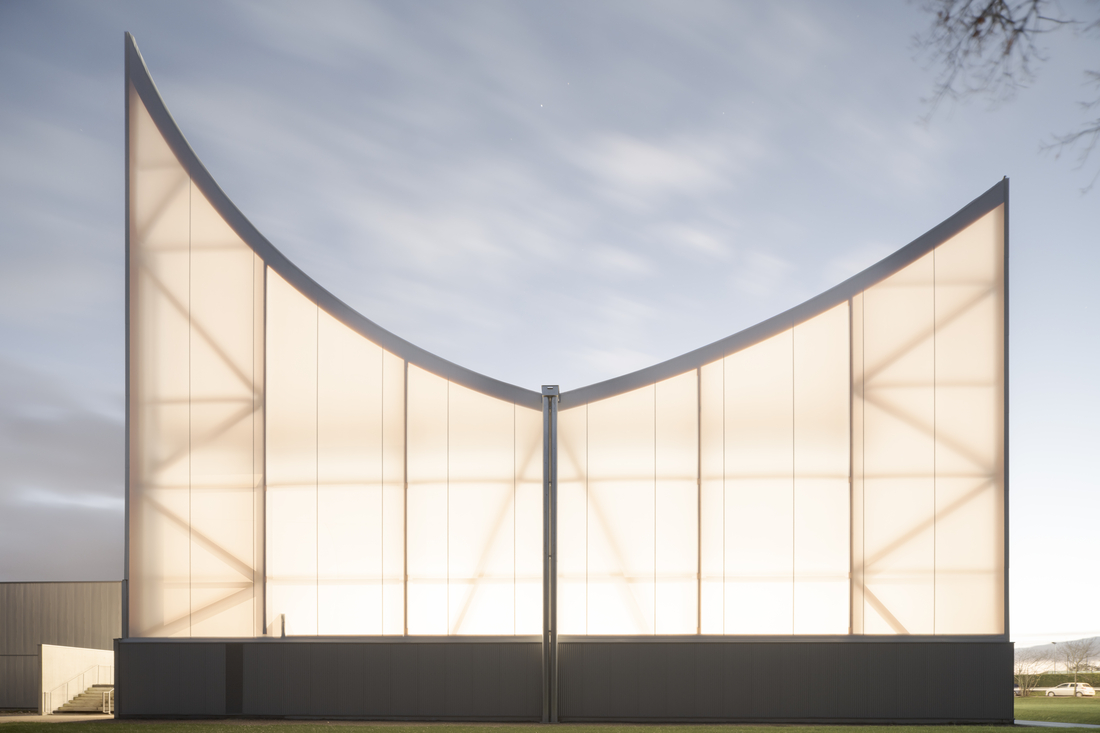 Façade d’un bâtiment sportif avec membrane textile translucide rétroéclairée, utilisant la toile Tenseo 902 S2.