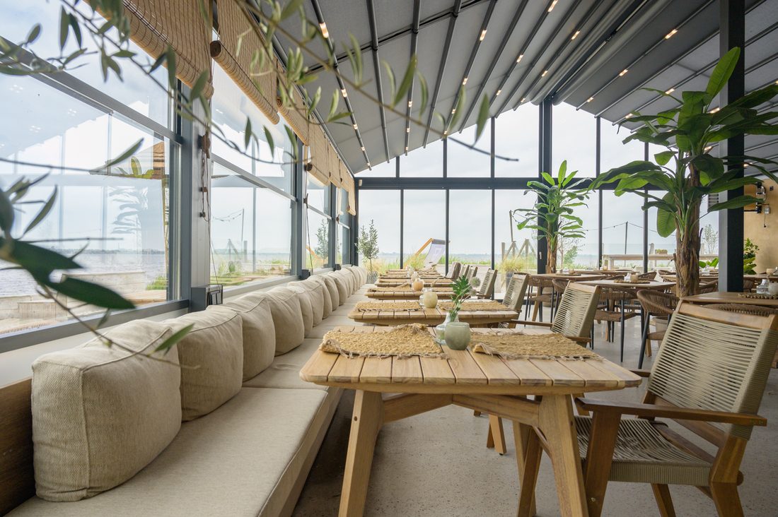 Beachfront restaurant interior with Soltis 96 Proof roof panels and natural wood furniture