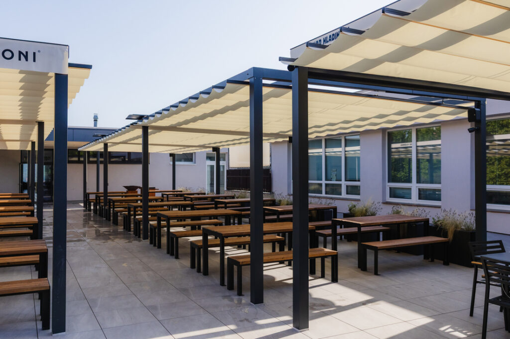 Grande terrasse de restaurant équipée de pergolas textiles rétractables et d’une structure aluminium moderne.