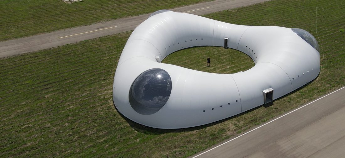 Structure textile circulaire vue du ciel, implantée en pleine nature.