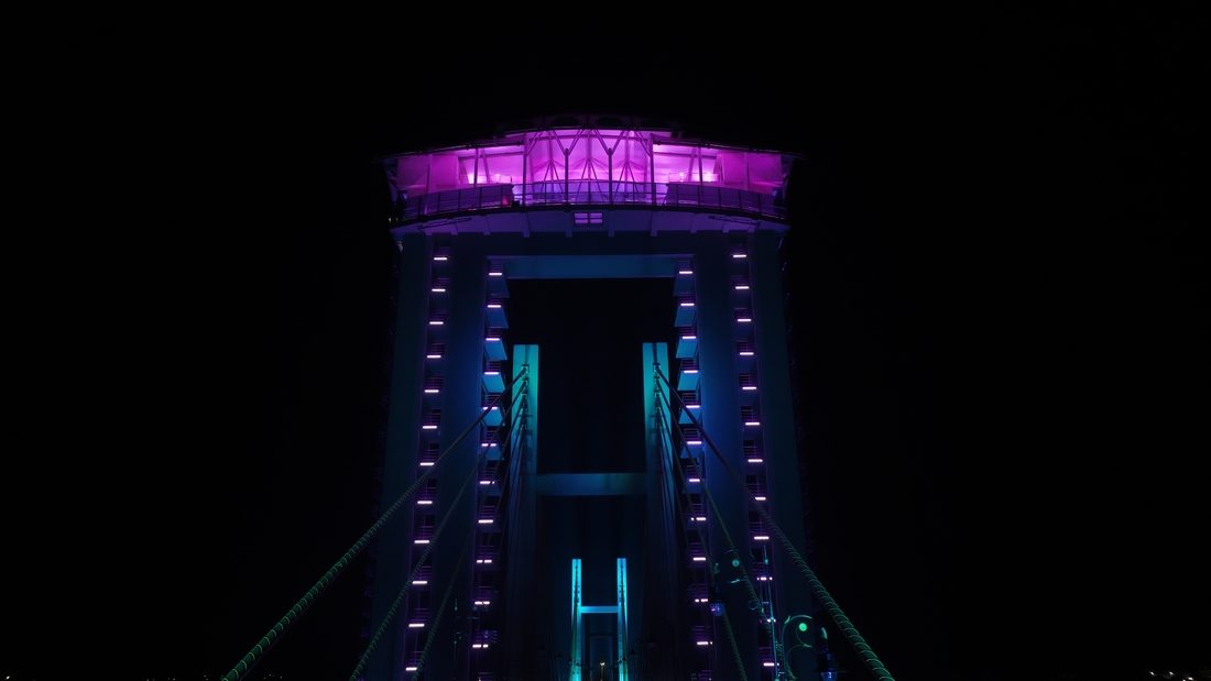 Pylône central de l’Ambhora Bridge éclairé en violet et bleu la nuit.