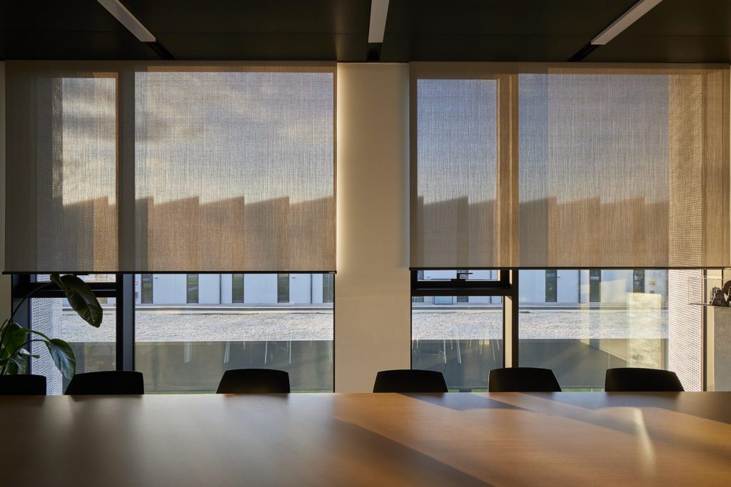 Stores enrouleurs intérieurs filtrant la lumière dans une salle de réunion