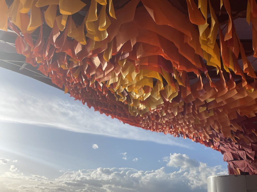 Close-up of red, orange and yellow fabric strips forming a gradient canopy inside Chaka Salt Lake Station
