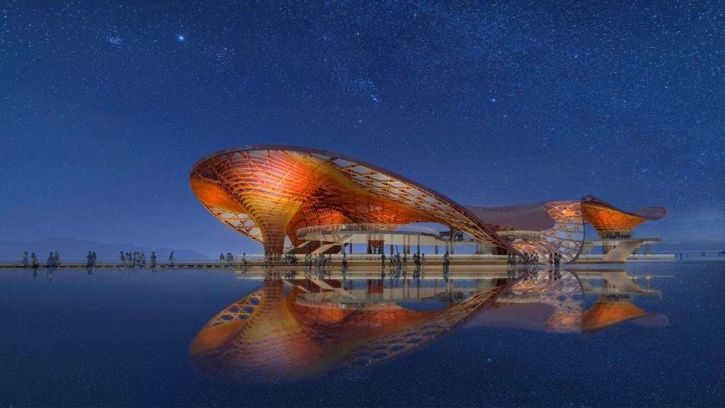 Night view of Chaka Salt Lake Station with illuminated red and orange roof reflected on the water.