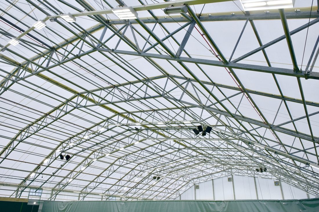 Vue intérieure d’une toiture en membrane composite souple Serge Ferrari sur charpente métallique, conçue pour couvrir un équipement sportif.