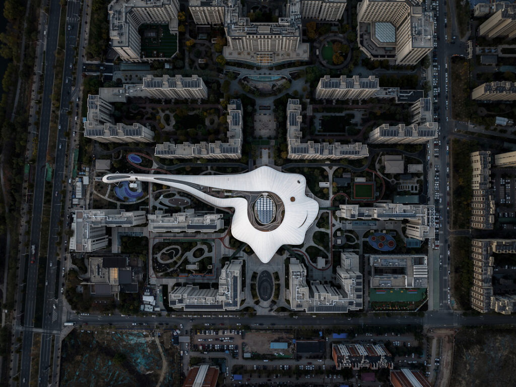 Vue aérienne d’un complexe architectural avec une vaste toiture textile blanche aux formes organiques, au cœur d’un ensemble urbain.