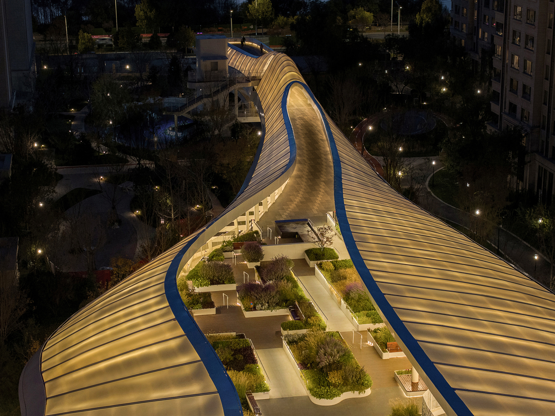 Vue aérienne de nuit d’un complexe architectural avec une toiture textile aux formes organiques