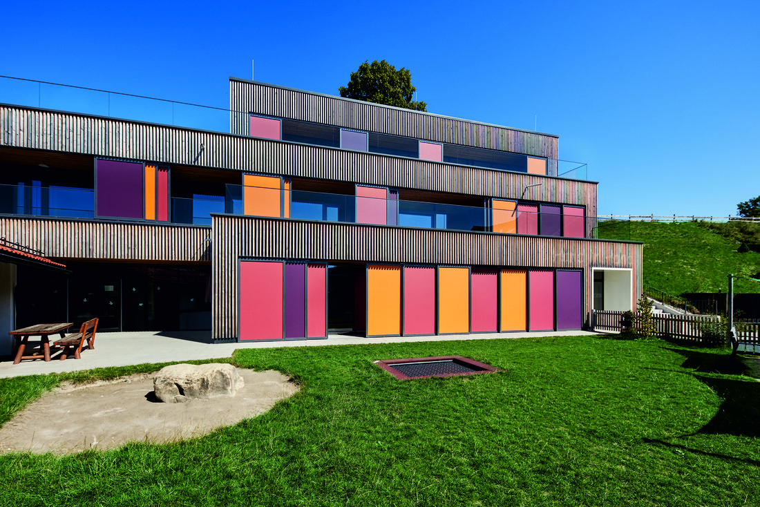 Vue d’ensemble d’une crèche moderne équipée de protections solaires textiles Soltis 92 aux couleurs vives.