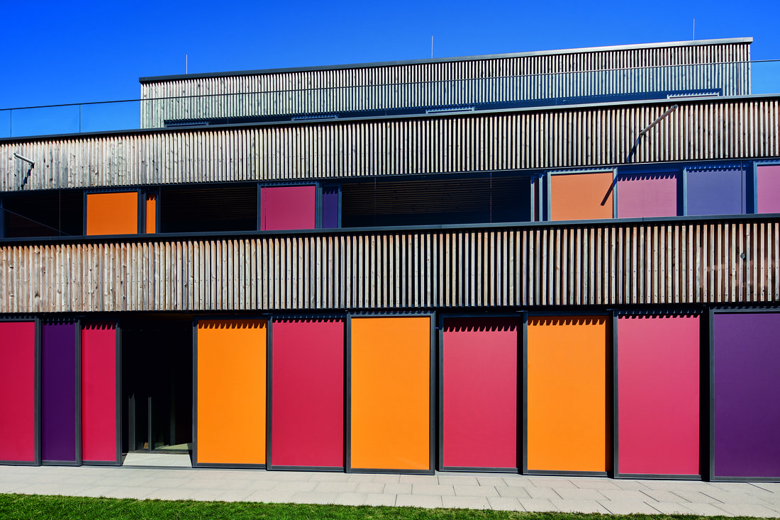 Façade d’une crèche contemporaine avec brise-soleil textiles colorés Soltis 92 intégrés à une structure en bois.