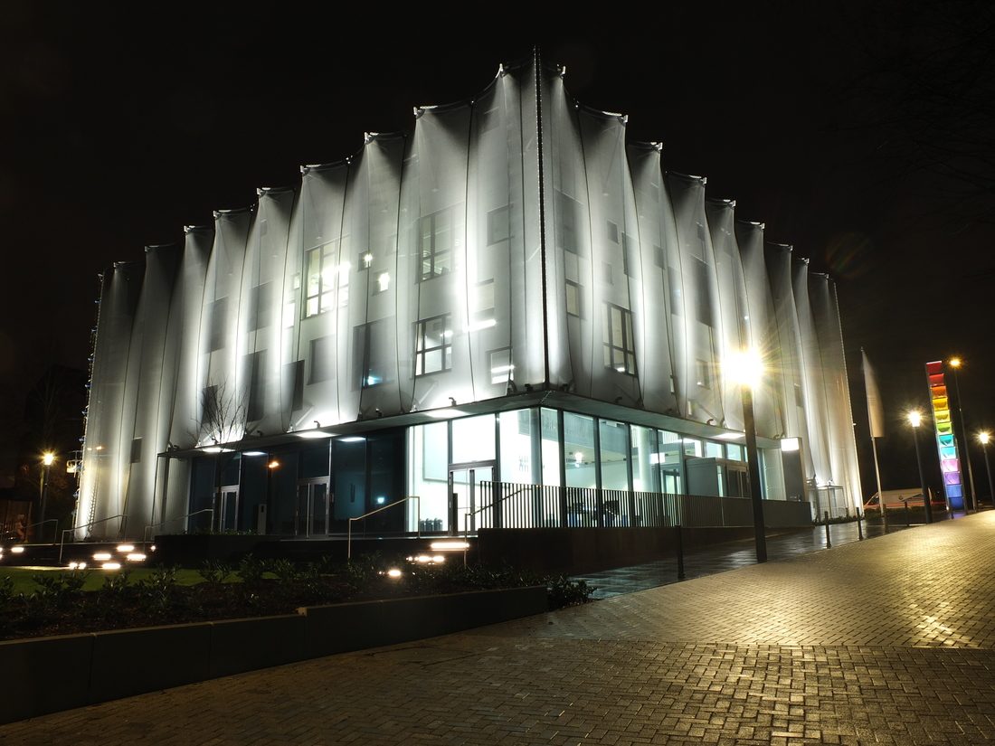 Façade textile rétroéclairée enveloppant un bâtiment la nuit