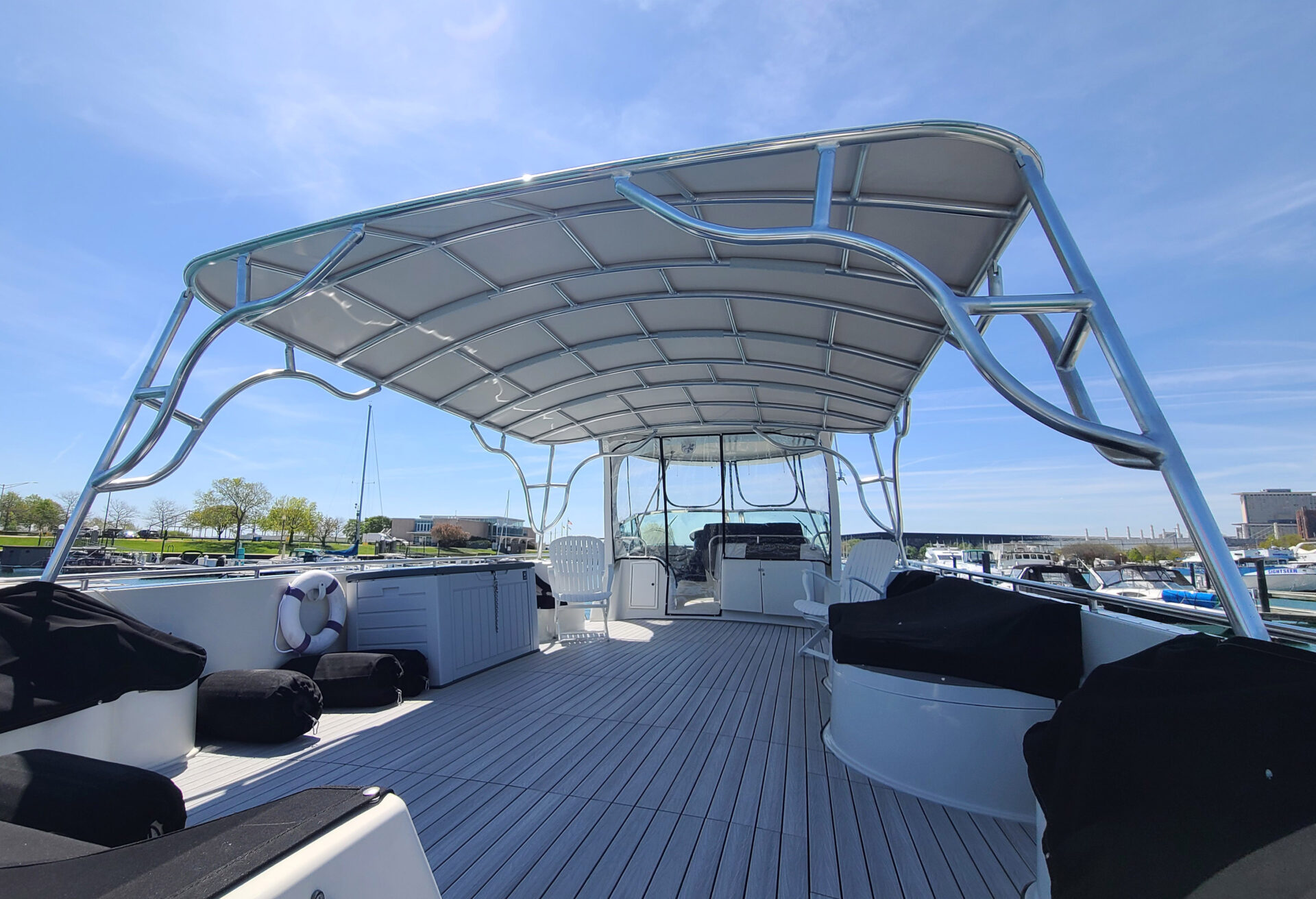 Wide interior view under the Stamoid Top canopy on the upper deck of a Bluewater Coastal Cruiser 68, with seating along both sides.