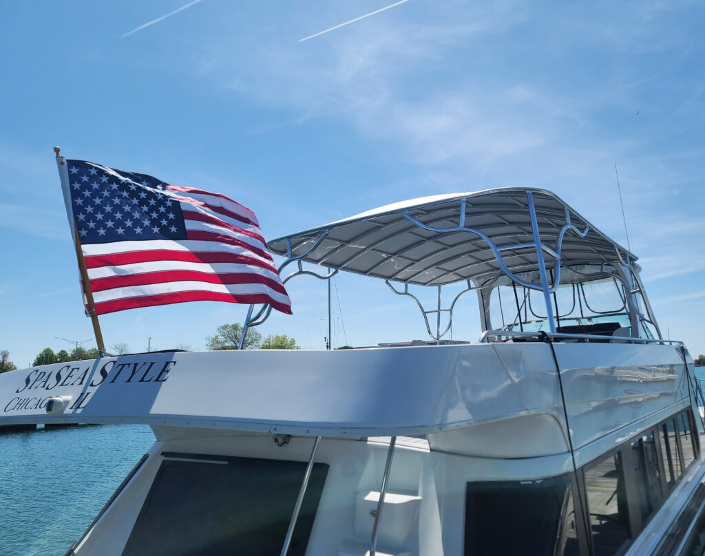 Rear view of a Bluewater Coastal Cruiser 68 with a Stamoid Top permanent upper-deck canopy and an American flag at the stern.