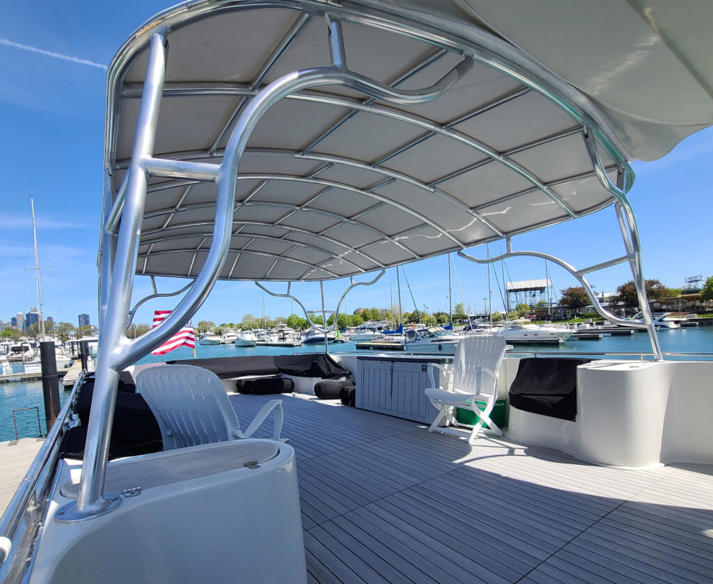 Under the Stamoid Top permanent canopy on a Bluewater Coastal Cruiser 68, showing the tubular frame and upper deck seating.