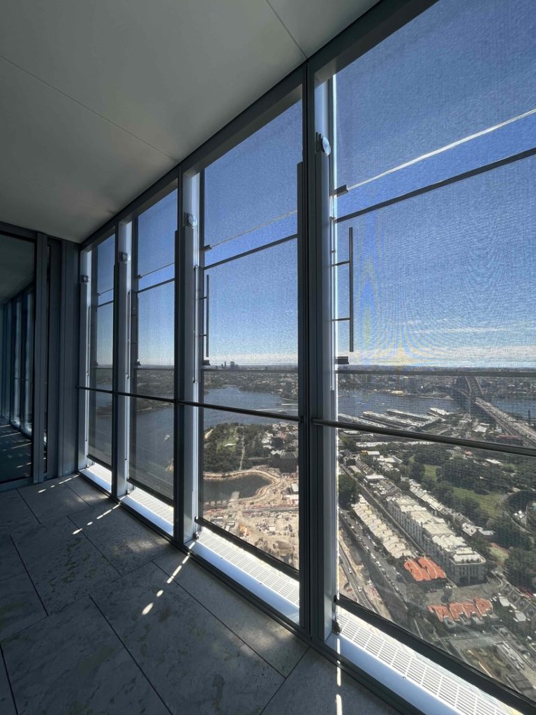 Vue intérieure d’un bâtiment équipé de stores en toile technique Serge Ferrari filtrant la lumière tout en préservant la vue panoramique.