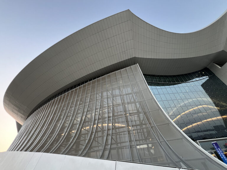 Vue en contre-plongée du bâtiment, combinant façade vitrée et structure textile translucide en membrane PTFE-GFM-52.