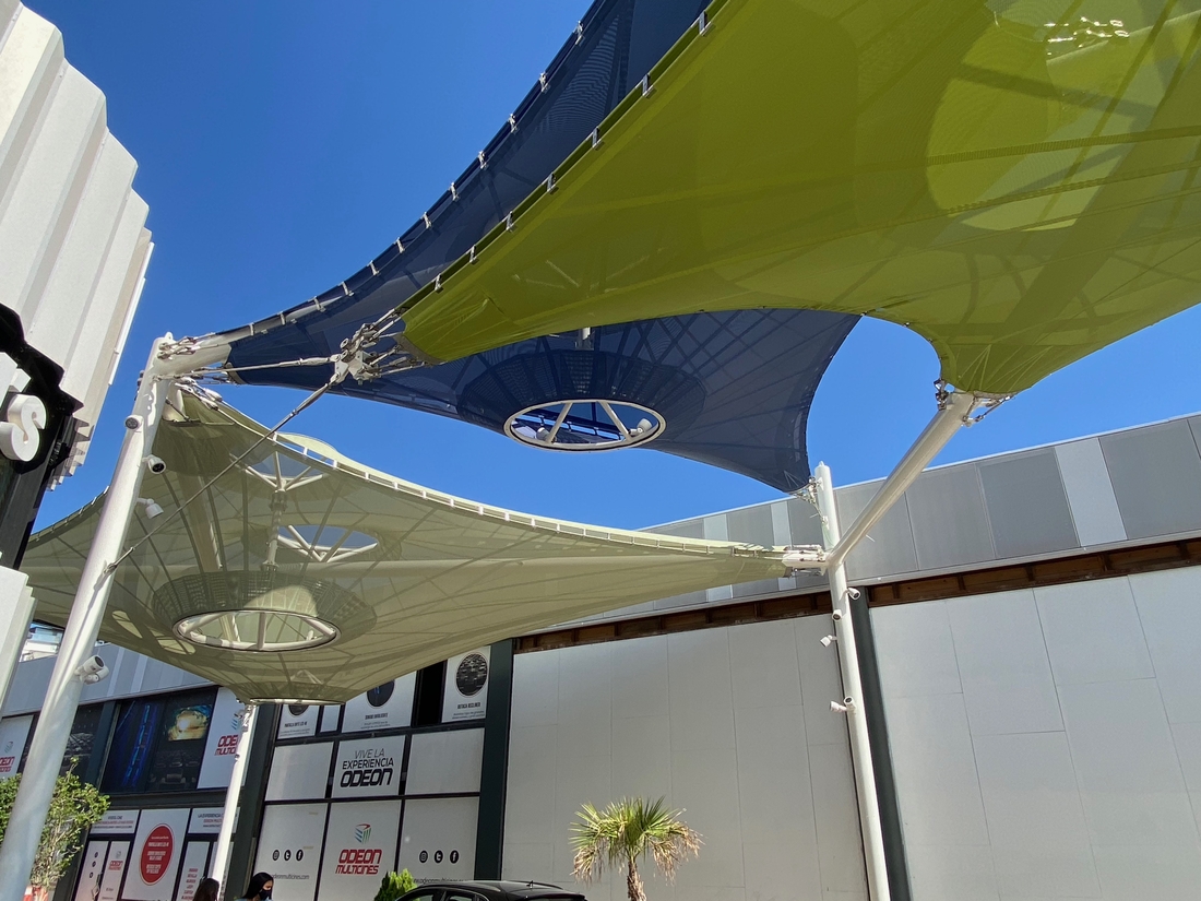 Vue en contre-plongée d'une voile d'ombrage textile tendue avec ses points de fixation