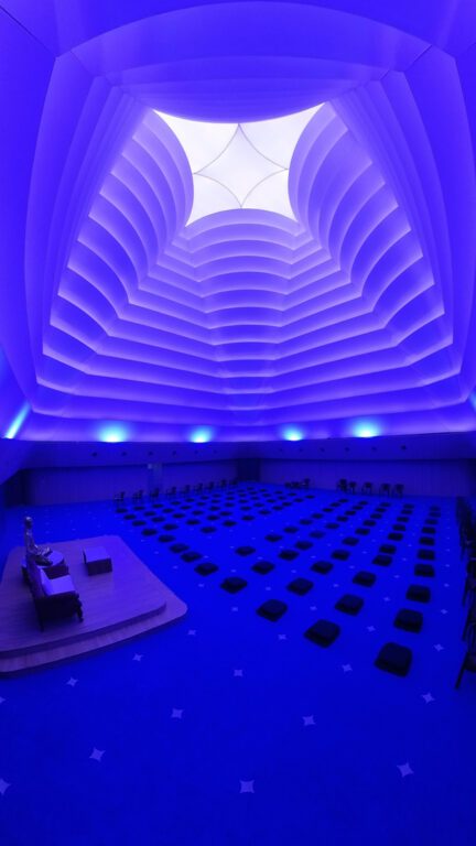 Plafond textile plissé illuminé en bleu au Shrimad Rajchandraji Meditation Center, créant une ambiance immersive et spirituelle.