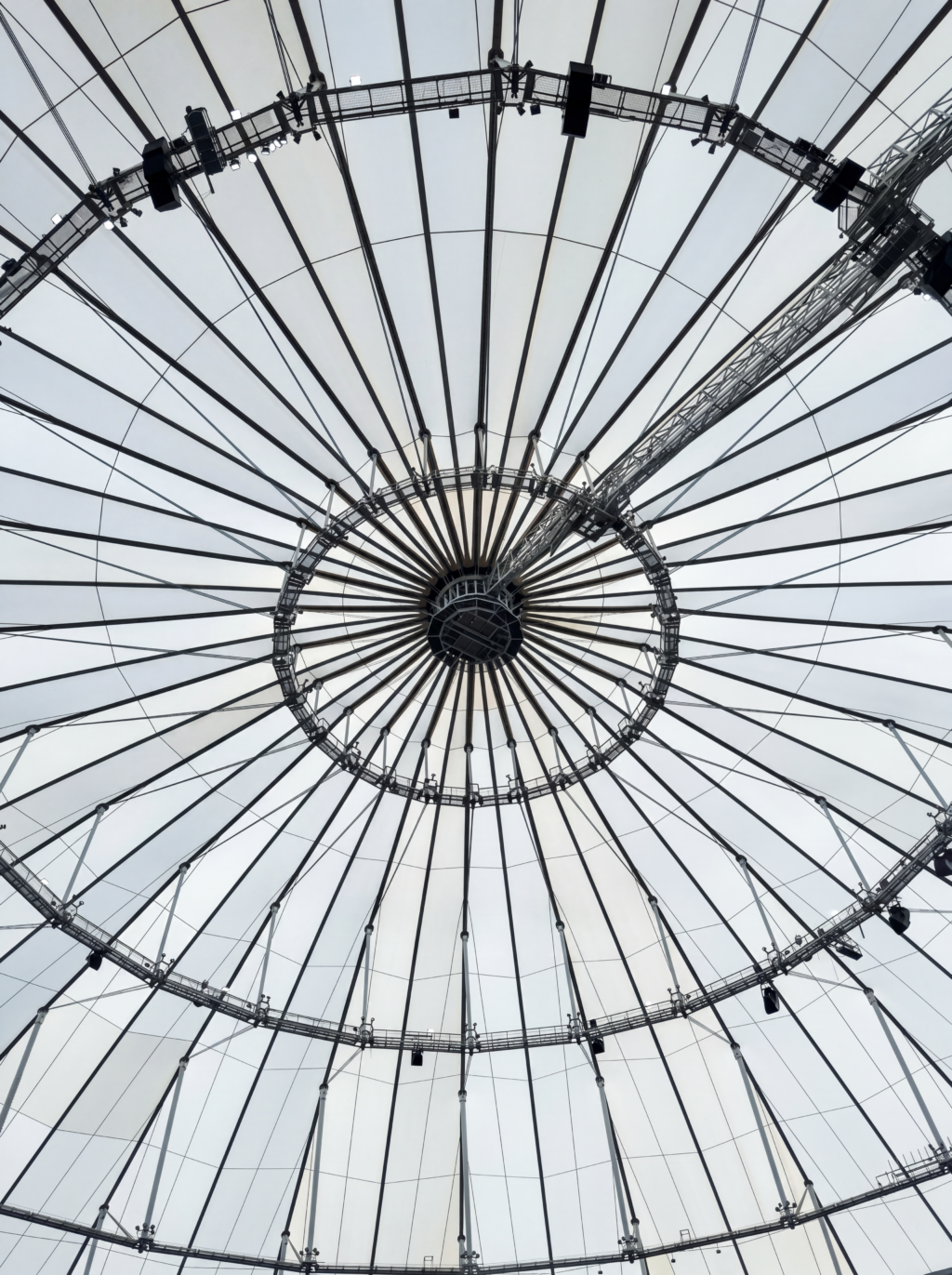 Upward view of the central compression ring and radial cable network supporting a tensile membrane roof.