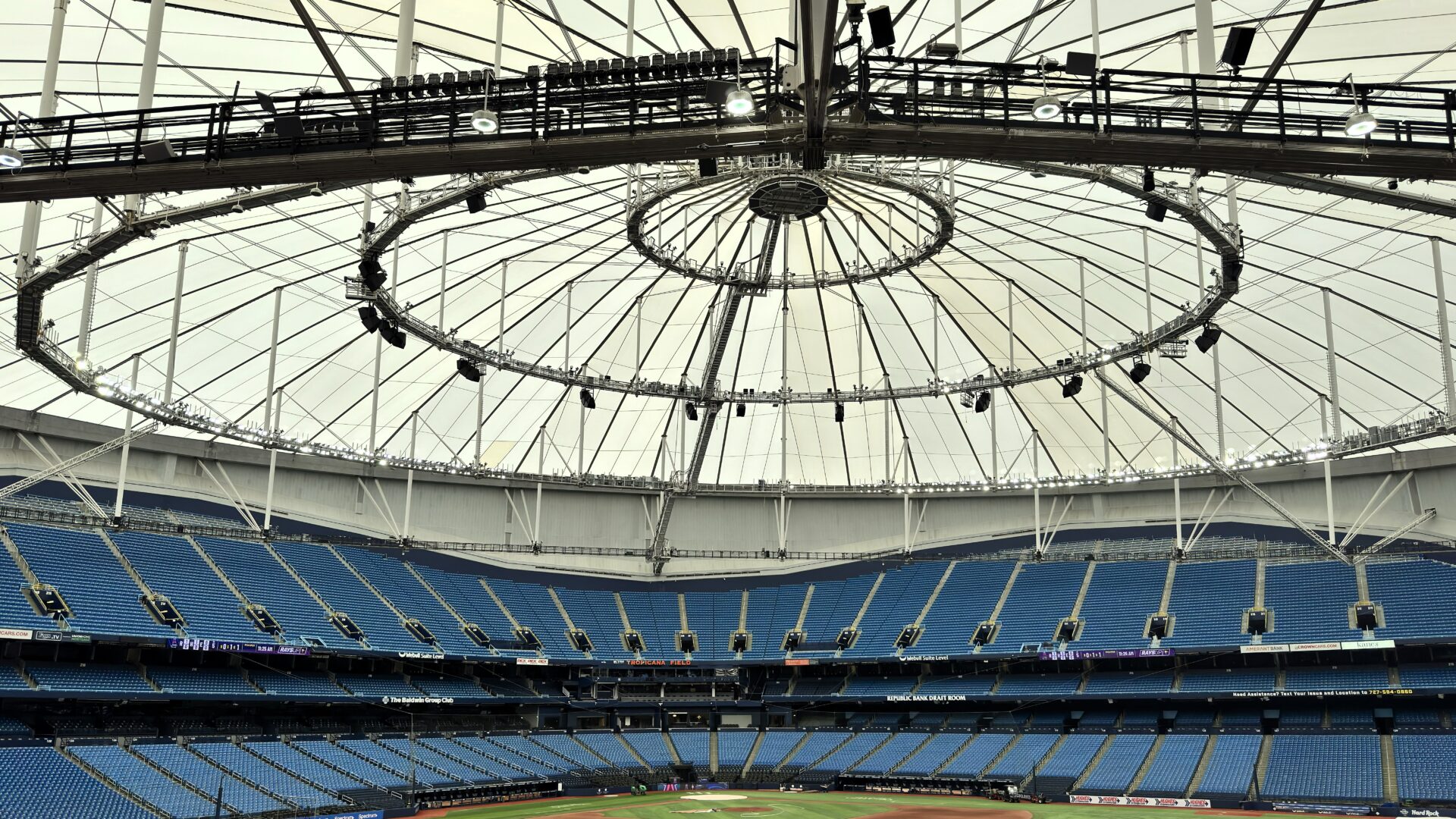 Interior view of Tropicana Field featuring blue stadium seating beneath a cable-supported tensile membrane roof structure.