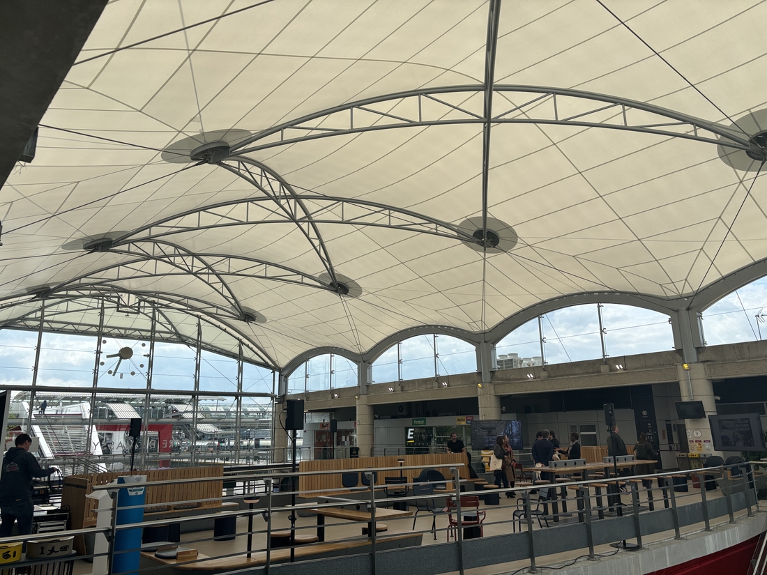 Vue intérieure de la gare de Massy TGV sous une vaste toiture textile soutenue par une structure métallique.