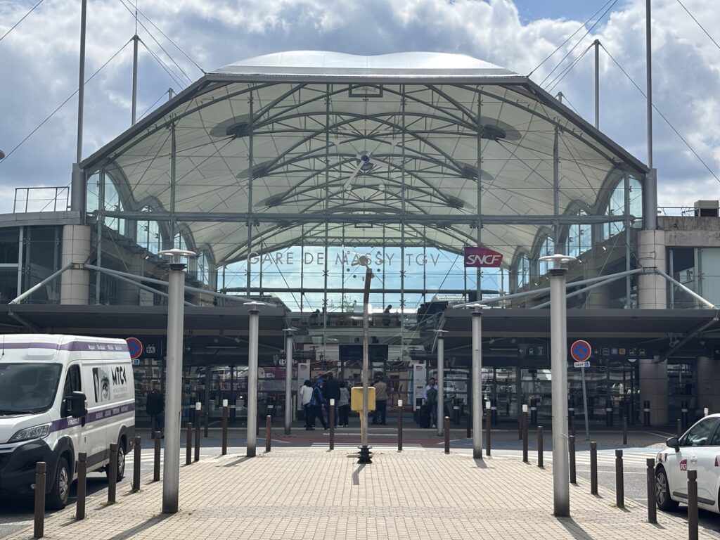 Façade vitrée de la gare de Massy TGV surmontée d'une toiture textile blanche.
