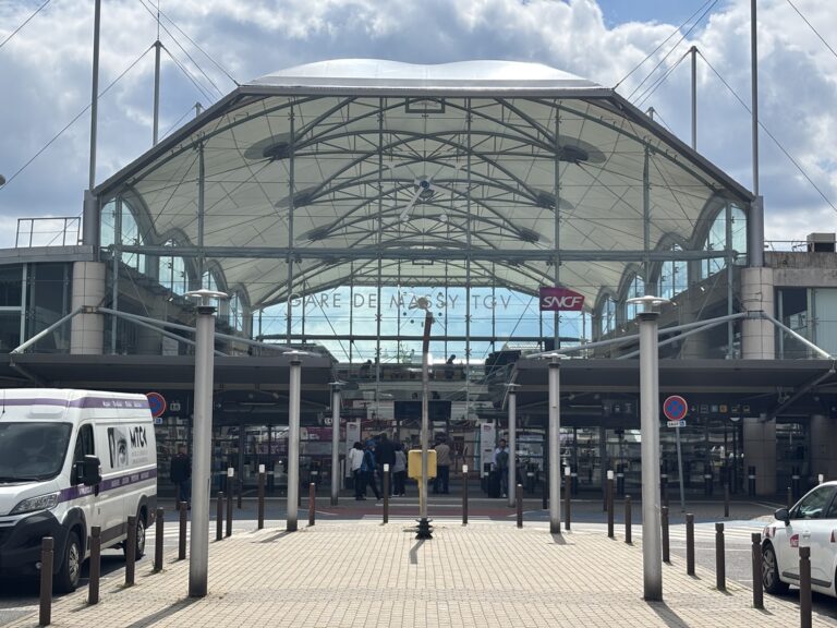 Façade vitrée de la gare de Massy TGV surmontée d'une toiture textile blanche.