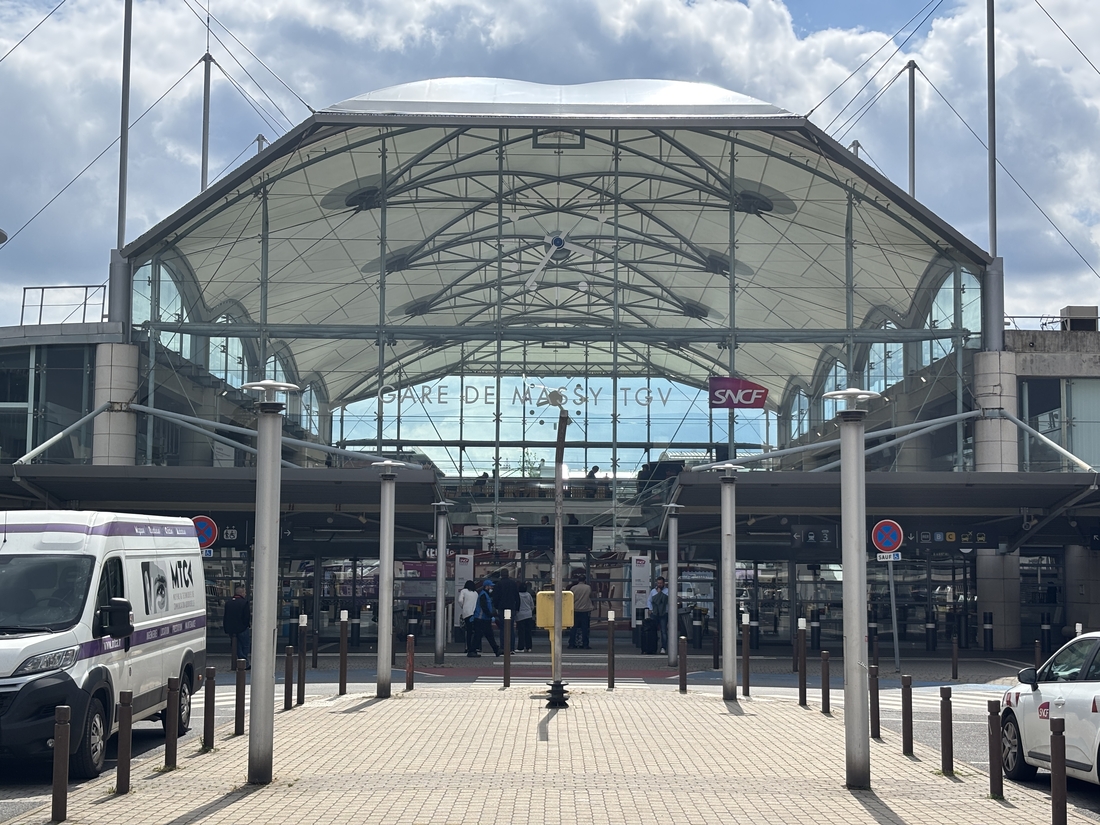 Façade vitrée de la gare de Massy TGV surmontée d'une toiture textile blanche.