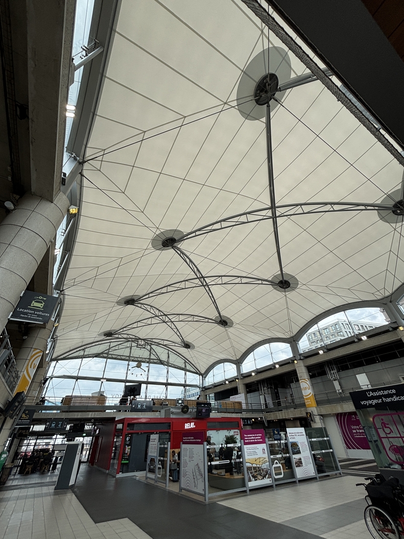 Hall de la gare de Massy TGV avec commerces sous une toiture textile lumineuse.
