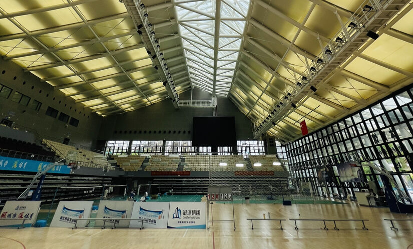 Vue intérieure d’une salle multisports avec toiture en membrane composite Serge Ferrari et puits de lumière central