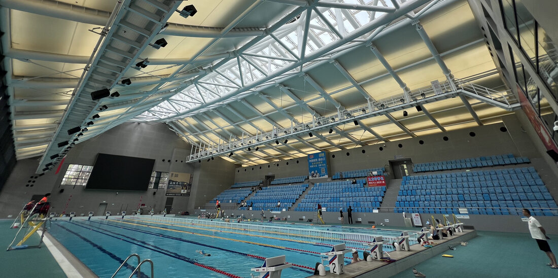 Centre aquatique couvert avec toiture en membrane composite Serge Ferrari et structure métallique apparente