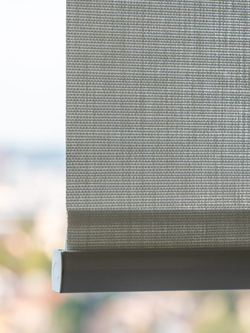 Store intérieur en toile technique avec barre de charge filtrant la lumière