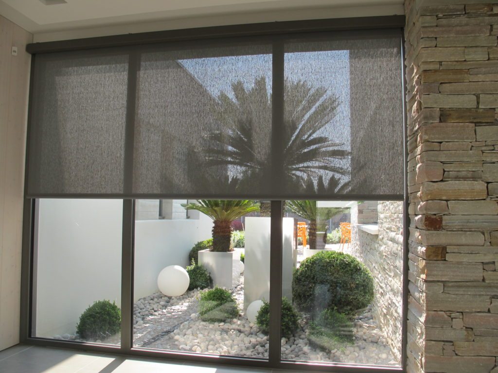 Store enrouleur intérieur en membrane composite souple Serge Ferrari sur grande baie vitrée pour confort thermique et anti-éblouissement