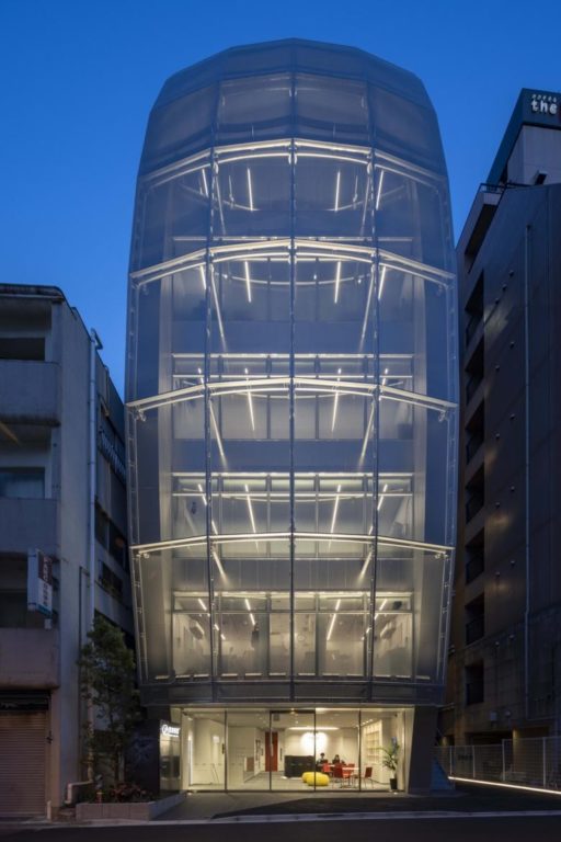 Daytime exterior view of the Building of Music in Tokyo with curved Serge Ferrari mesh façade and external staircase.