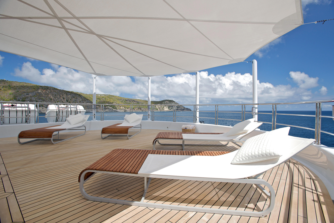 Pont de yacht avec voiles d’ombrage textiles et transats face à la mer