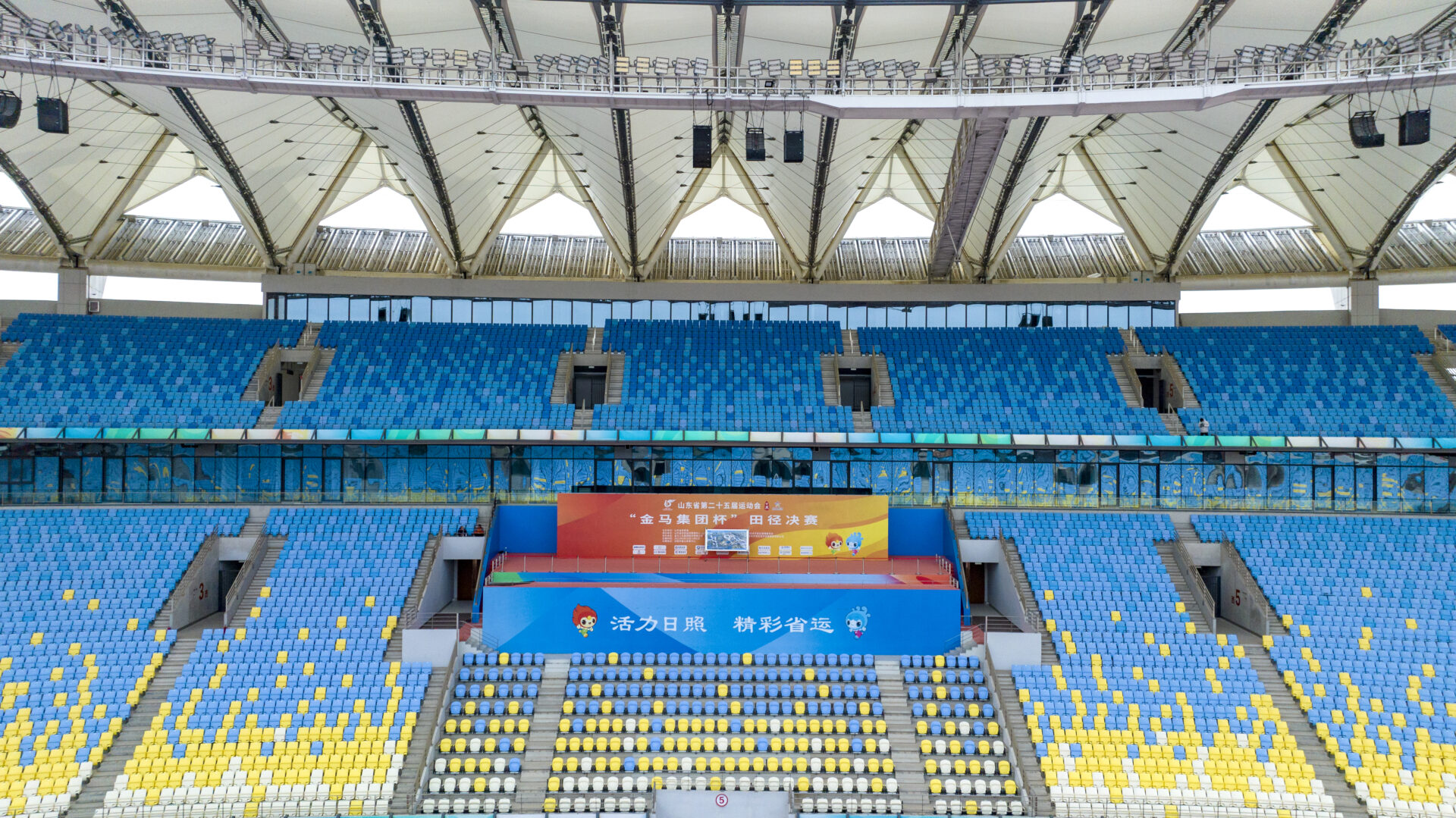 Interior view of Kuishan Stadium showing seating areas beneath the PTFE tensile roof