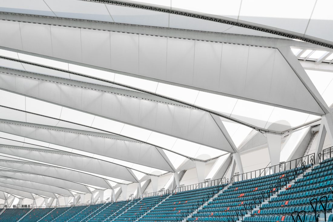Interior view of tensile roof panels above stadium seating rows.