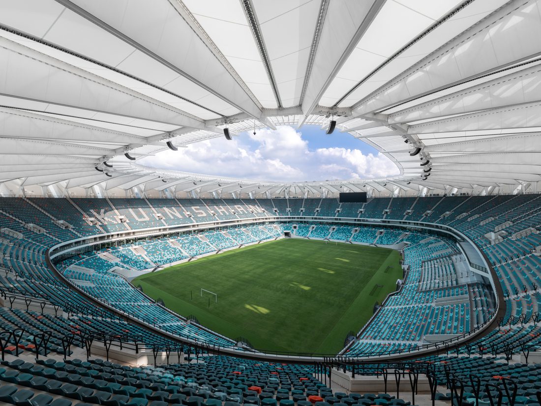 Wide interior view of Kunshan Stadium’s seating bowl and tensile roof structure.