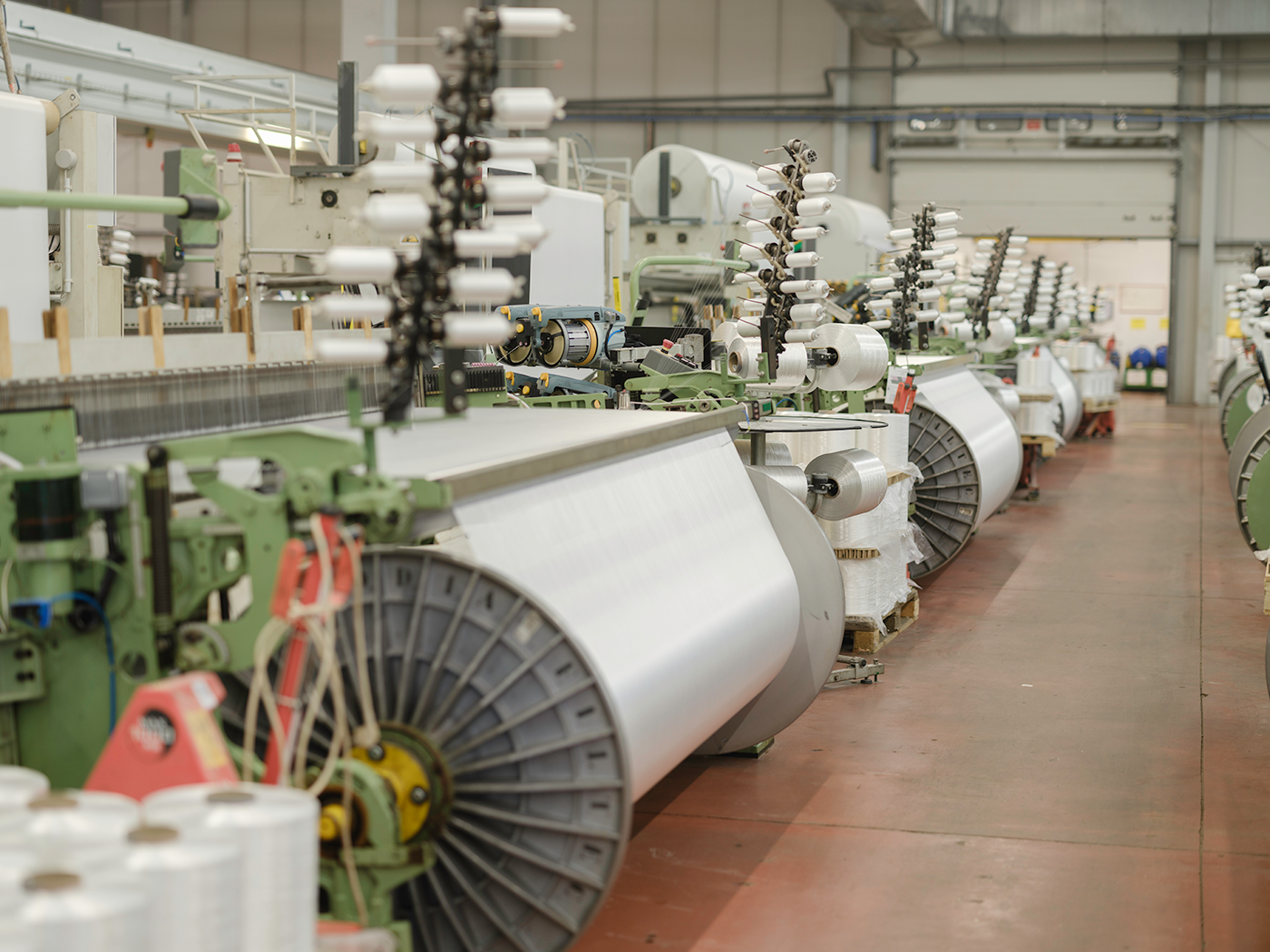 Grandes machines de tissage en fonctionnement dans l’atelier de fabrication des toiles composites du Groupe Serge Ferrari