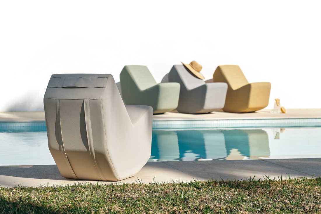 Fauteuil lounge beige au premier plan près d’une piscine avec autres fauteuils en arrière-plan.